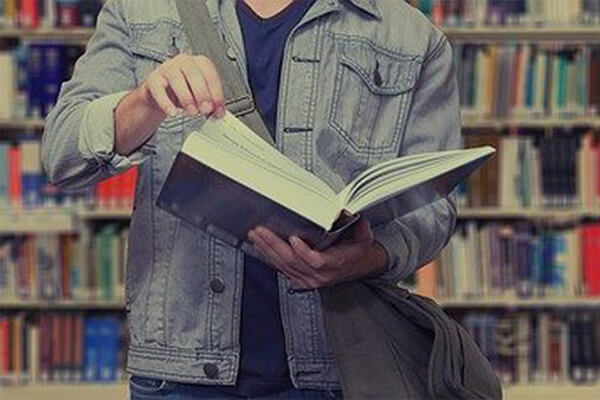 Rapaz consultando livro na biblioteca